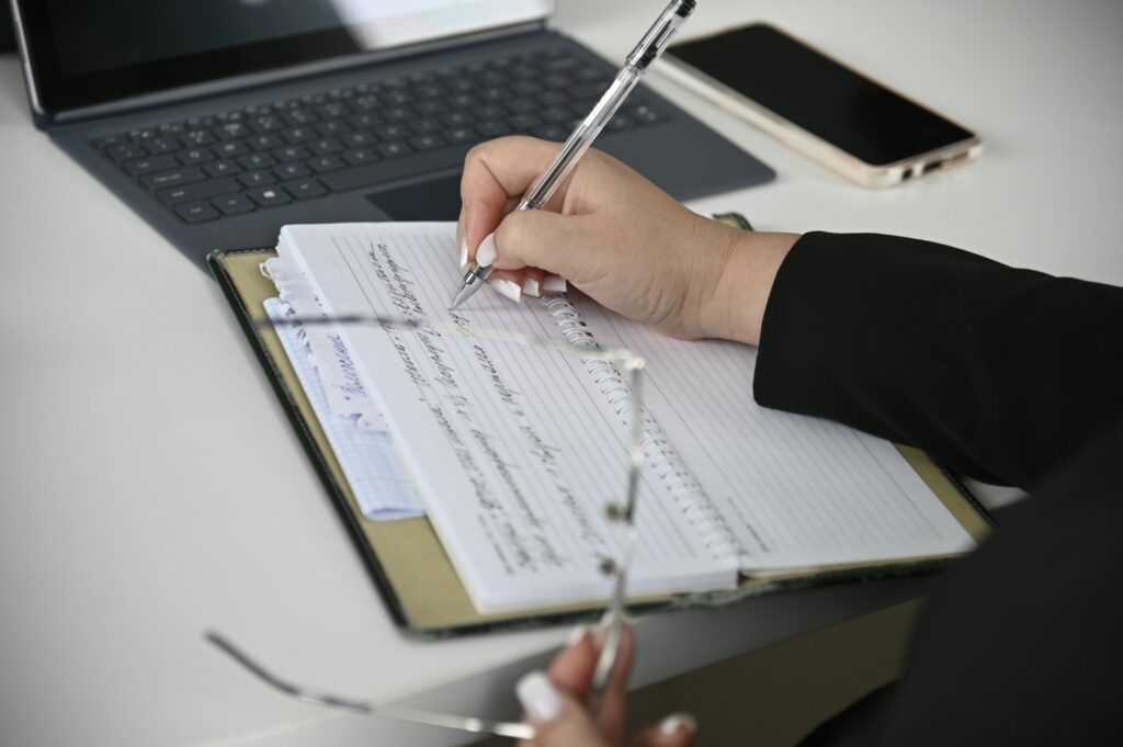 Person writing in a notebook on a desk