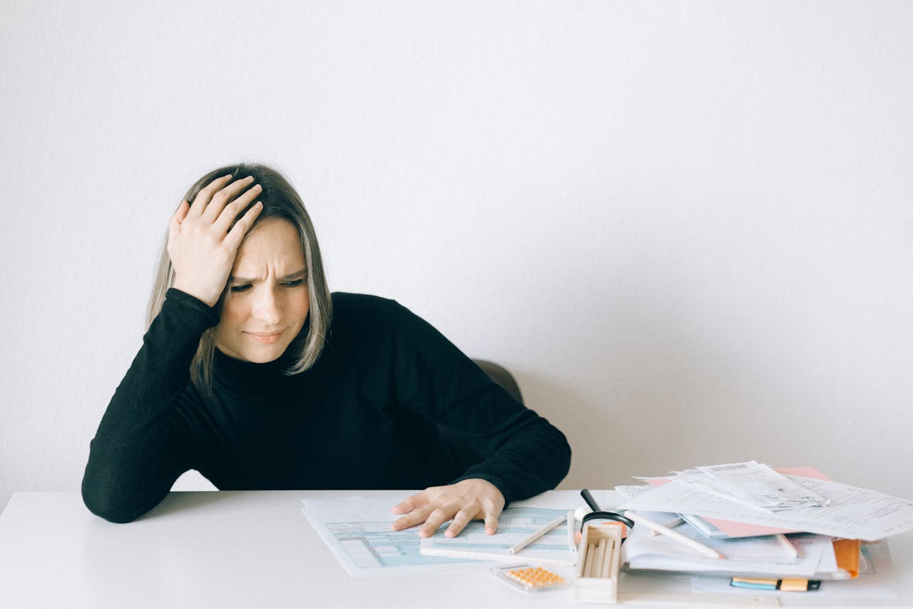 Stressed Woman at Desk Going Through Tax Paper Work