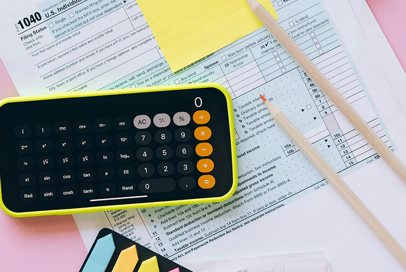 A desk with a calculator, tax forms and paperwork