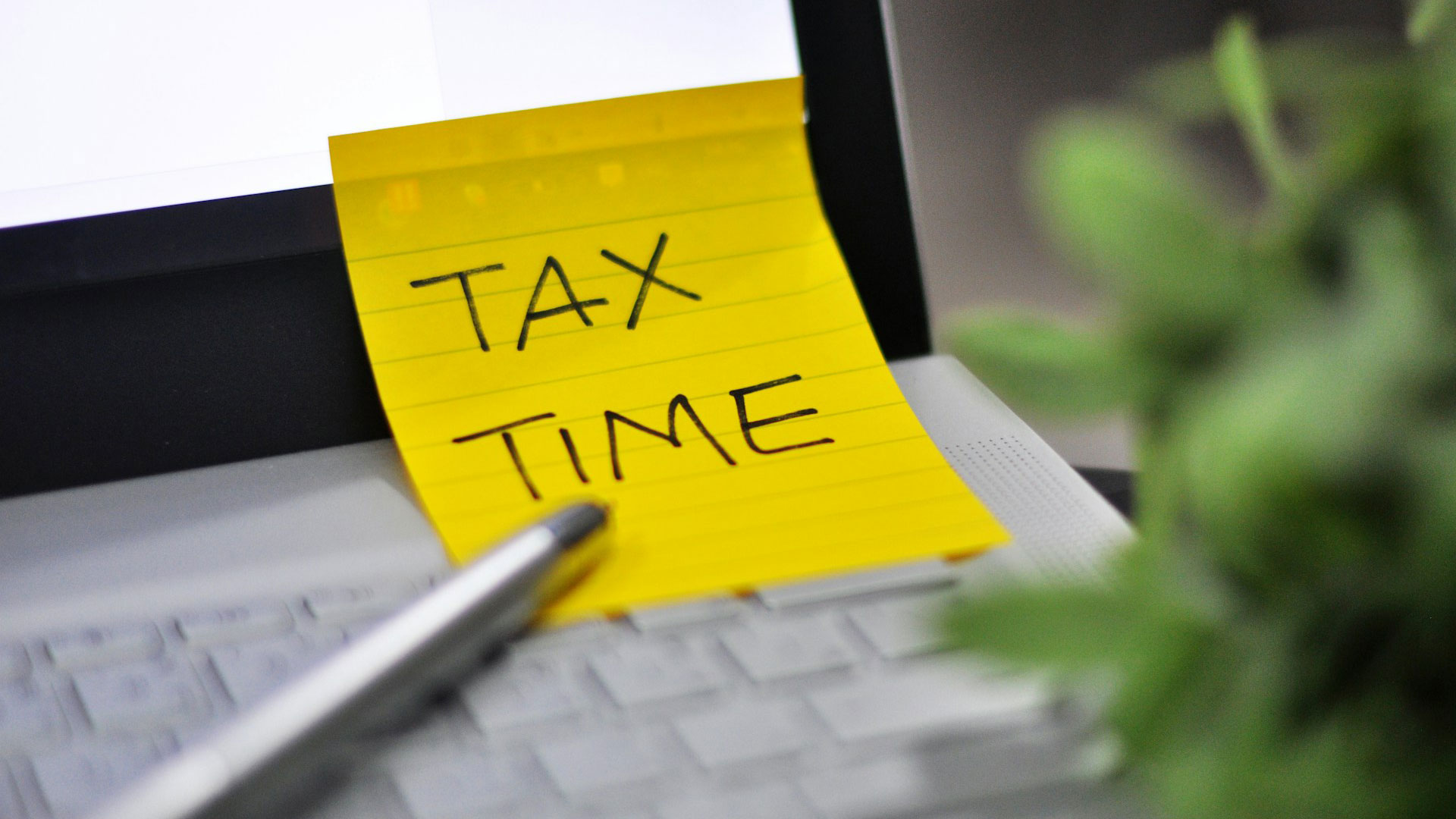 A yellow sticky note with a tax time reminder.